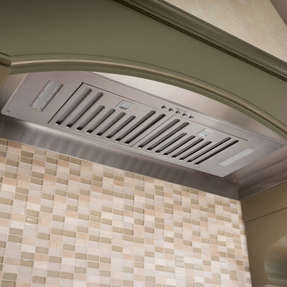 Stainless steel range hood mounted above a tiled kitchen backsplash.