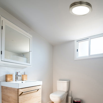 Modern bathroom with toilet, sink, and mirror under a ceiling light.