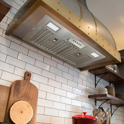 Kitchen with a modern range hood above a tiled wall.