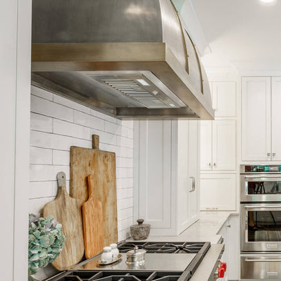 Modern kitchen with stainless steel appliances and wooden cutting boards on the stove.