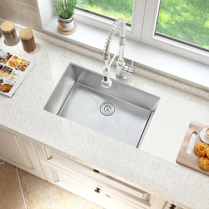 Stainless steel kitchen sink with faucet on a light-colored countertop.