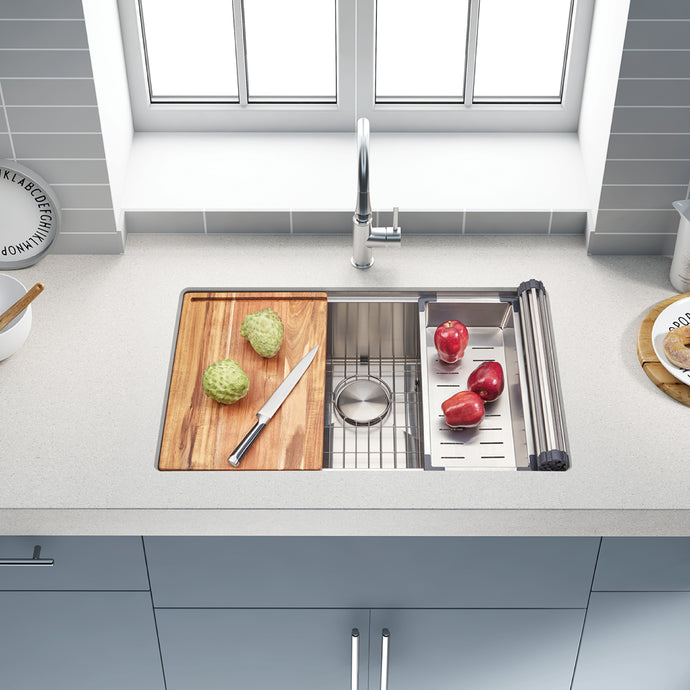 Modern kitchen sink with cutting board, knife, and vegetables on a light gray countertop.