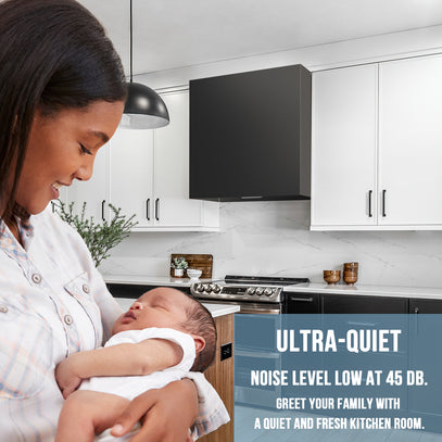 Woman holding a baby in a modern kitchen with text about ultra-quiet noise level.