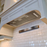 Stainless steel range hood in a kitchen with white tiled walls
