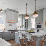 Modern kitchen with gray cabinets, white countertops, and brass pendant lights.