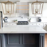Modern kitchen with white island, gray cabinets, and gold pendant lights.