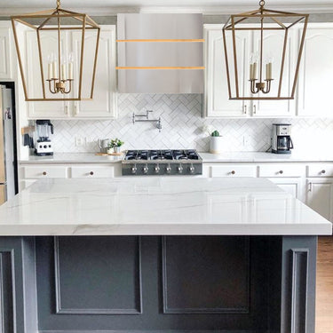 Modern kitchen with white island, gray cabinets, and gold pendant lights.