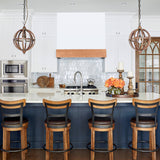 Modern kitchen with white cabinets, stainless steel appliances, and wooden bar stools.