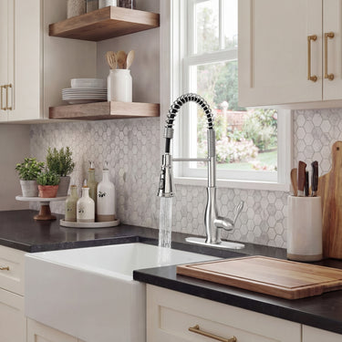 Modern kitchen with a farmhouse sink, black countertop, and decorative elements.