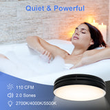 Woman relaxing in a bubble bath with a ceiling light fixture labeled 'Quiet & Powerful' on a stone wall background.