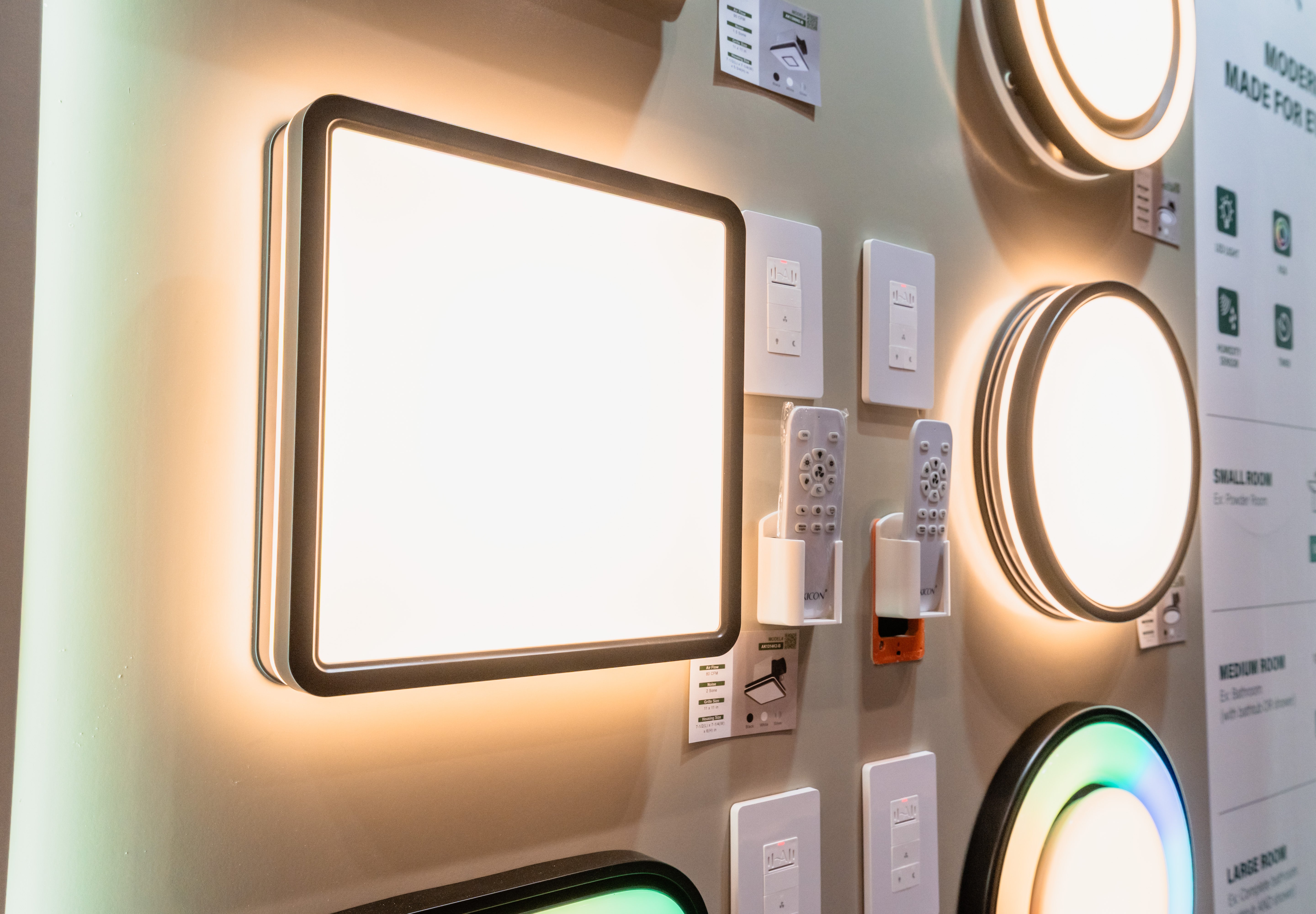 Various wall-mounted light fixtures on a display wall with labels.