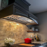 Modern kitchen with a black range hood, tiled backsplash, and a red pot on the stove.