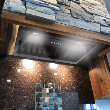 Kitchen with stone wall, wooden cabinets, and a modern range hood.