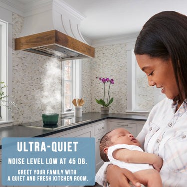Woman holding a baby in a modern kitchen with text about ultra-quiet noise level.