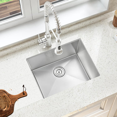Stainless steel kitchen sink with faucet on a light-colored countertop.