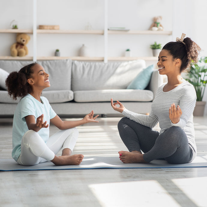 Two young girls practicing yoga together in a living room.