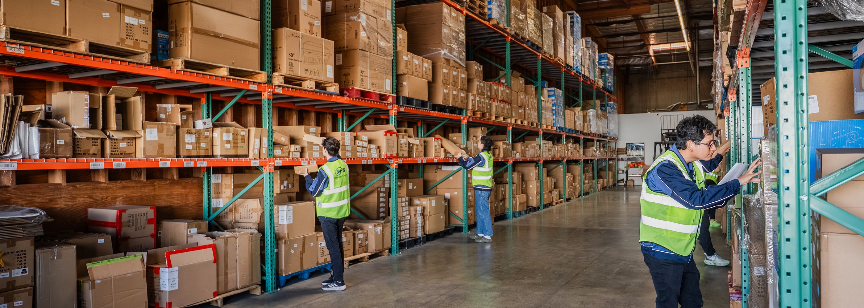 Workers in a warehouse with shelves stocked with boxes